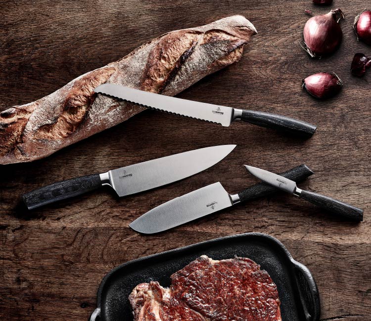 Germancut Favorites Messer liegend auf Holz mit Baguette, Zwiebeln und Steak